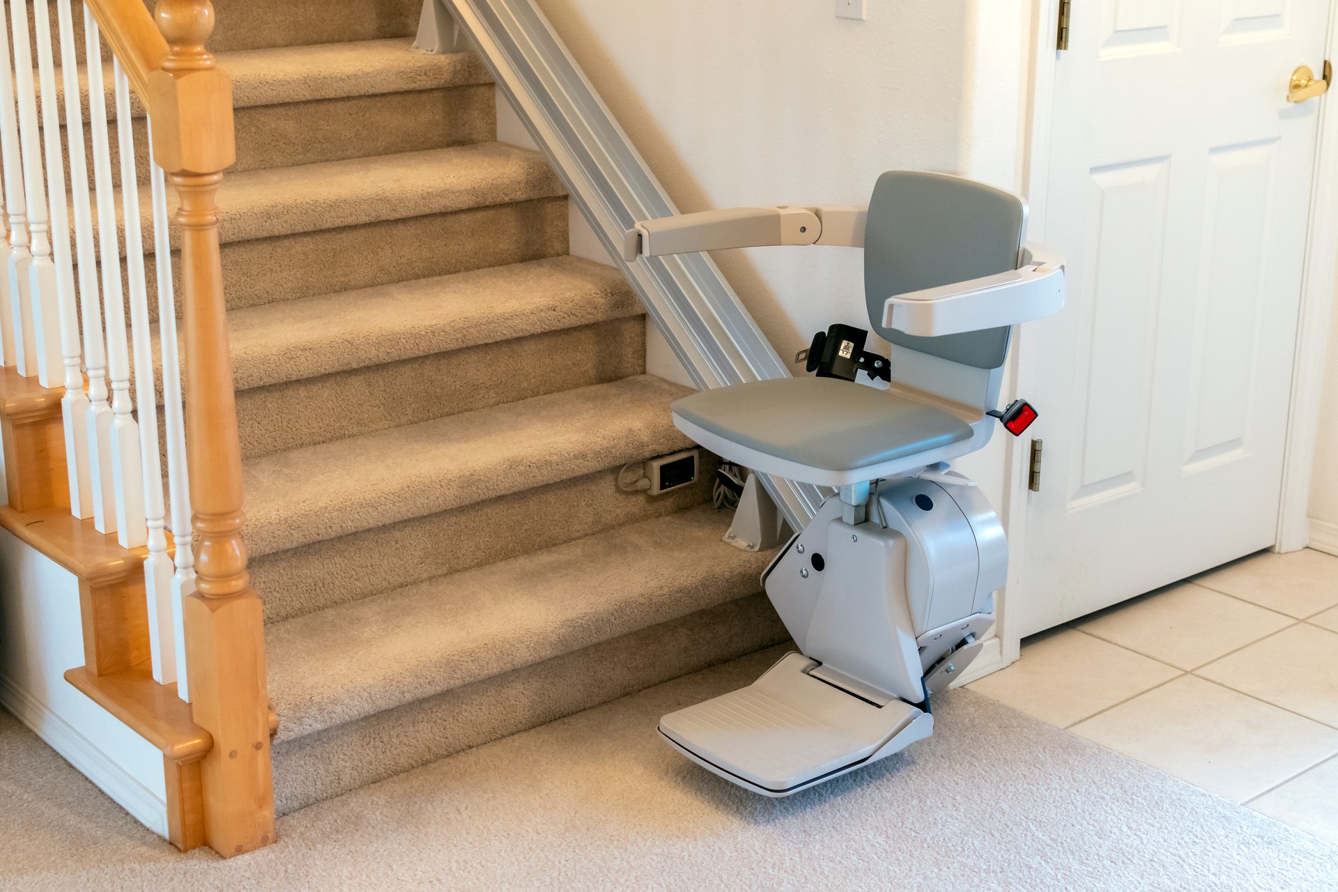 An electric, motorized chair or stair lift for persons with disabilities on a carpeted staircase in a two story residential home.