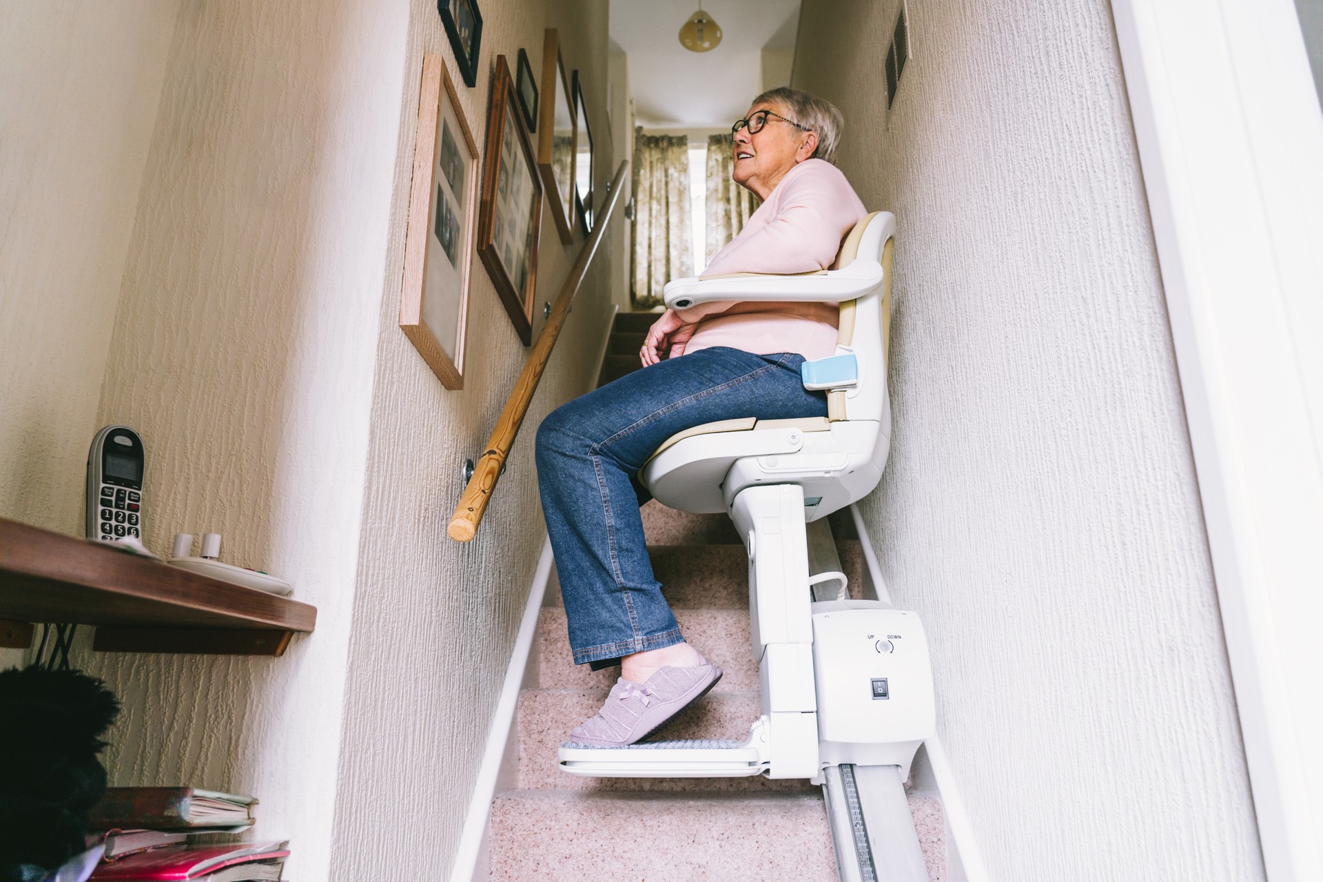 Senior woman using automatic stair lift on a staircase at her home. Medical Stairlift for disabled people and elderly people in the home. Selective focus.